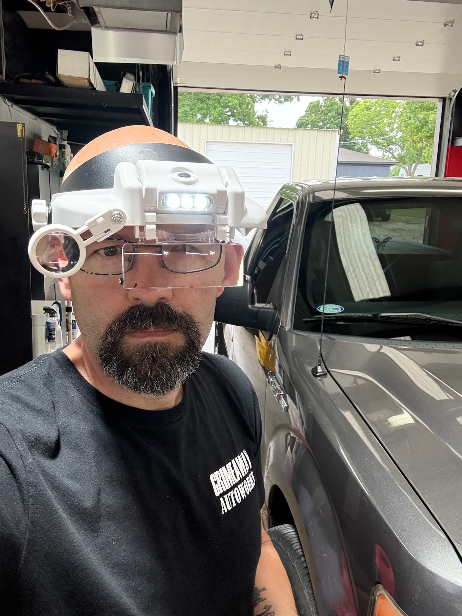 Grimeaway Autoworks technician wearing inspection magnifiers beside a vehicle