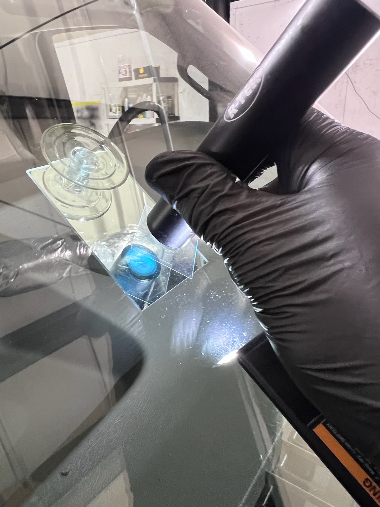 Technician curing resin on a windshield chip