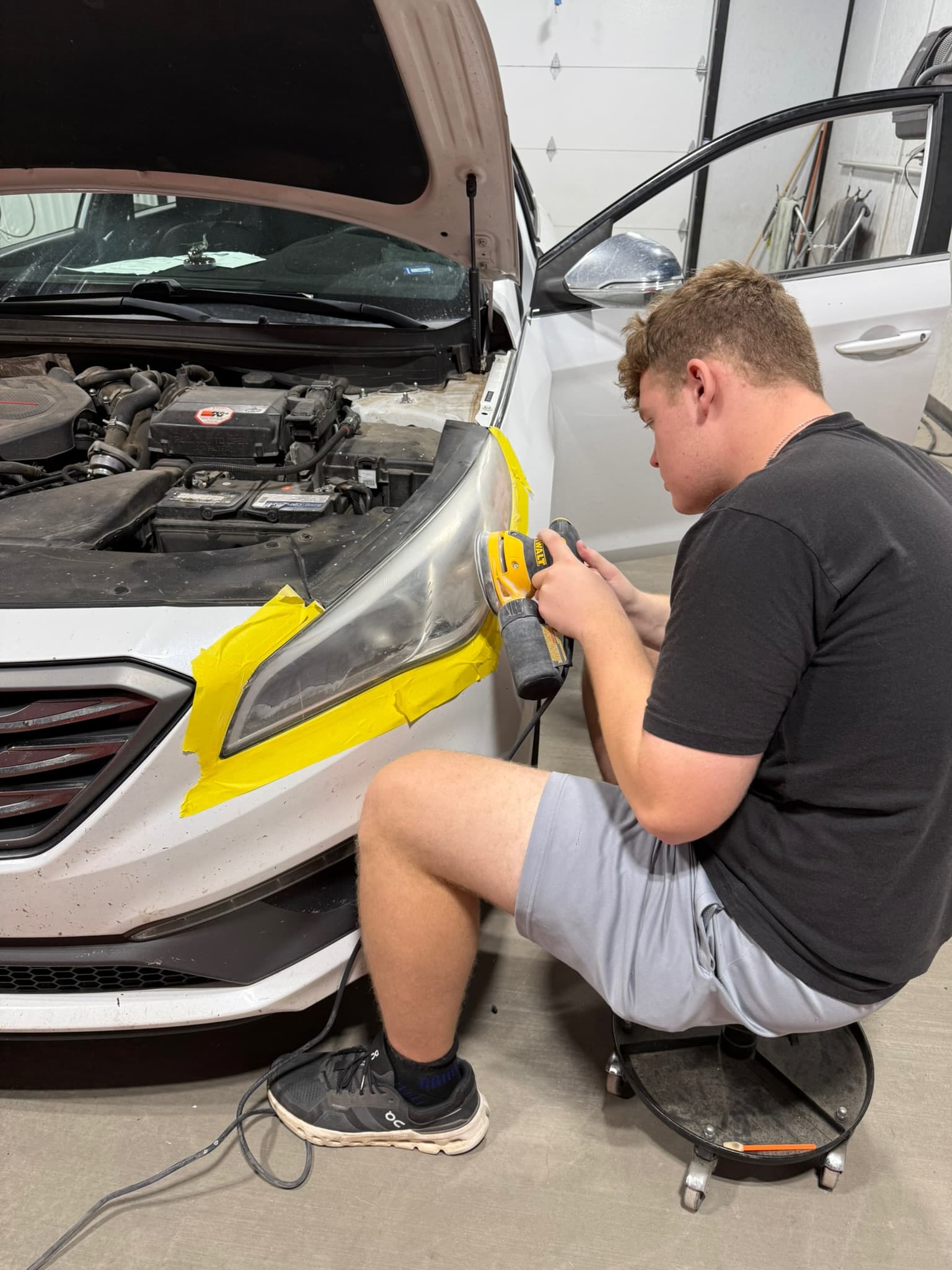 Technician polishing a masked headlight