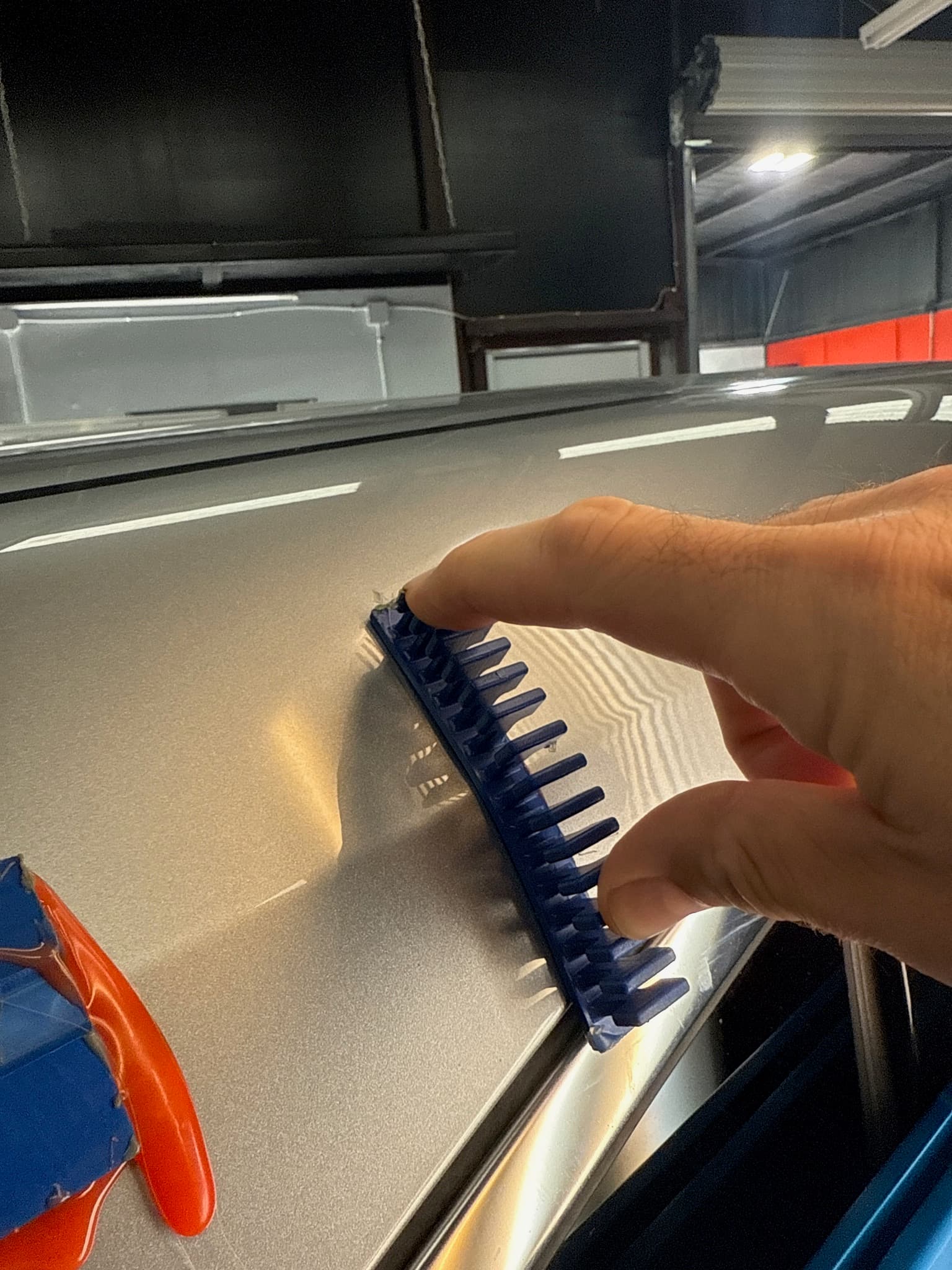 PDR tool working a dent out of a silver fender